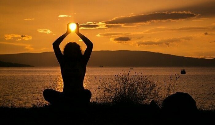 DR Image d'une femme assise qui tient le soleil entre ses mains