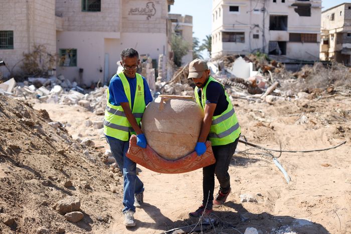 Deux hommes portant une amphore antique sur un champs de fouilles archéologique