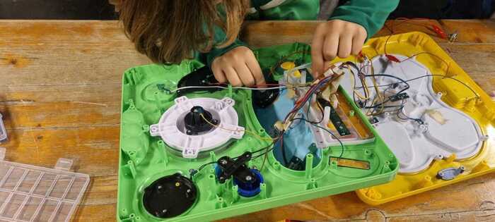 un enfant pencher sur un jouet électronique ouvert en train de le bidouiller.