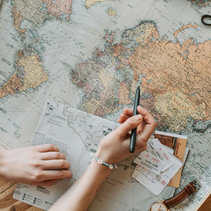 Une personne tient un stylo au dessus d'une carte du monde ouverte