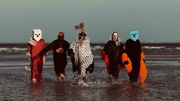 DR Les 5 membres du groupe sont sur la plage avec des déguisements