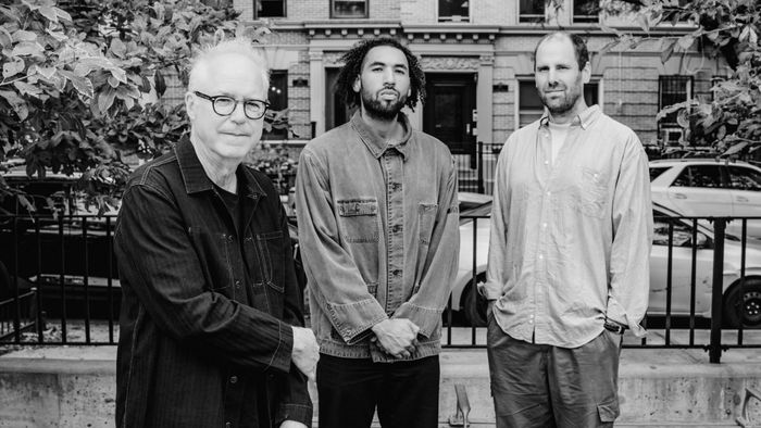 Photo en noir et blanc avec Bill Frisell et ses deux musiciens posant dans la rue