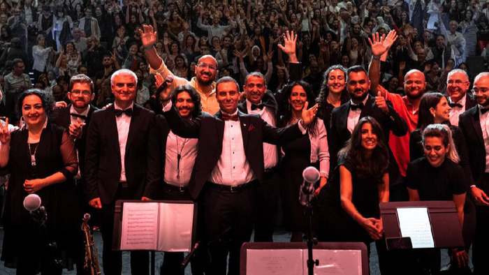 Photo de l'orchestre dos au public avec les mains en l'air