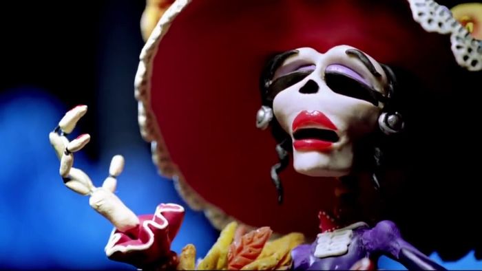 Une jolie femme squelette avec rouge à lèvre, fard à paupières violet et sombrero.