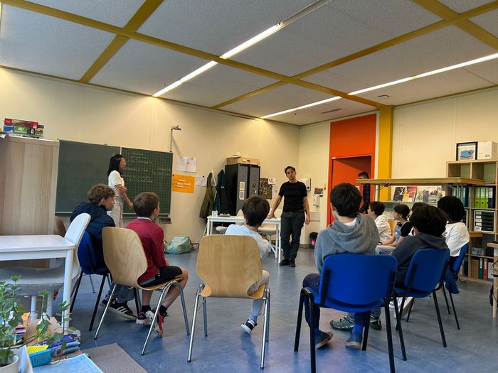 Image d'un atelier avec des enfants en rond assis sur des chaises face à un intervenant.