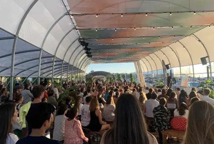 Personnes assises sous une tonnelle, écoutant une autre parler au fond