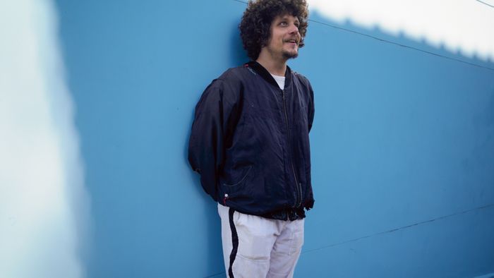 Portrait de Chico Chico debout contre un mur bleu