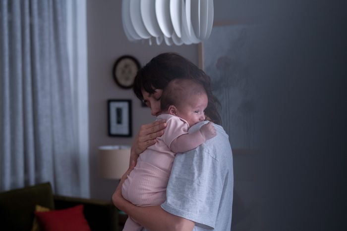 Femme tenant un bébé dans les bras dans une pièce de la maison.