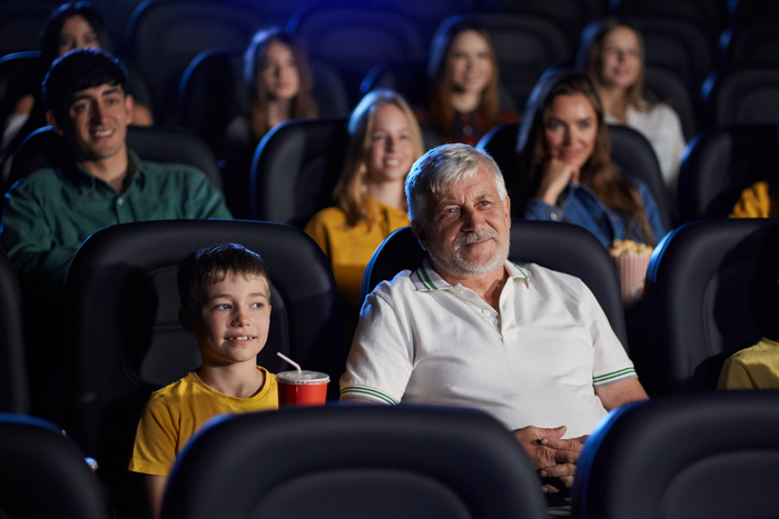 Personne âgée avec son petit-fils en train de regarder un film au cinéma