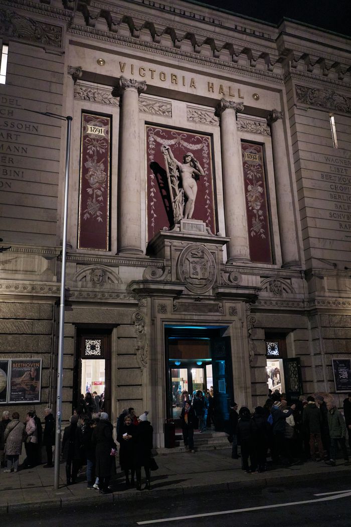 Photo de l'entrée du Victoria Hall de nuit avec du public