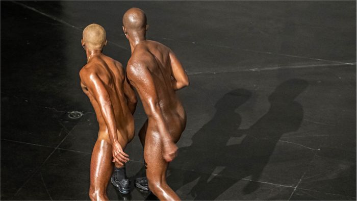 Deux hommes de dos nus, un public les regarde