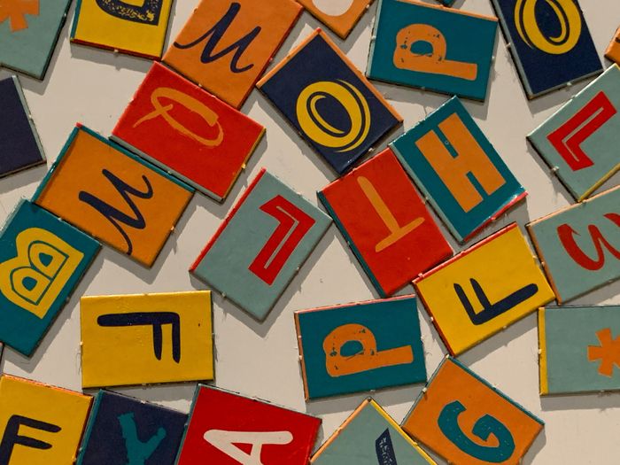 Une photo en couleur qui représente des lettres de l'alphabet en couleur, sur des pièces en carton, de format rectangulaire.