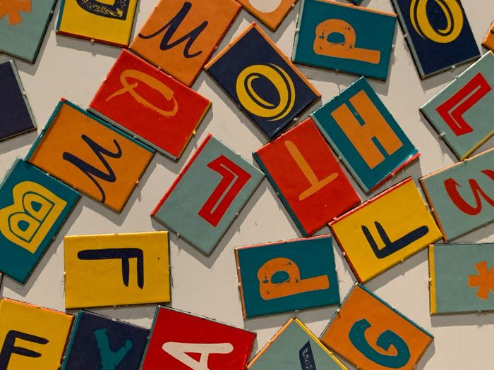Une photo en couleur qui représente des lettres de l'alphabet en couleur, sur des pièces en carton, de format rectangulaire.