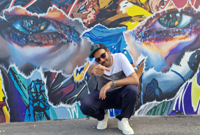 DR Un portrait de Dj Toots devant un tag coloré.