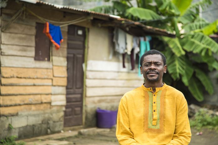 Un homme de couleur devant une maison
