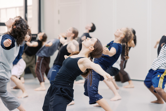 Un groupe de danseurs lève les yeux au ciel les bras écartés