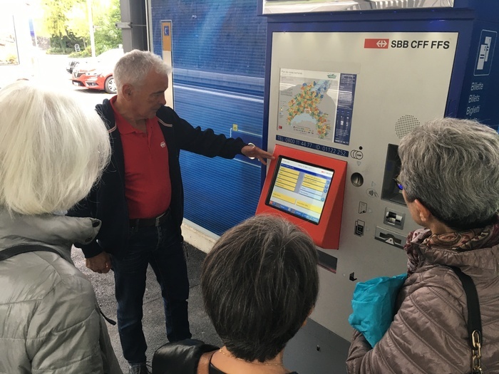 Seniors autour d'une borne de tickets de train