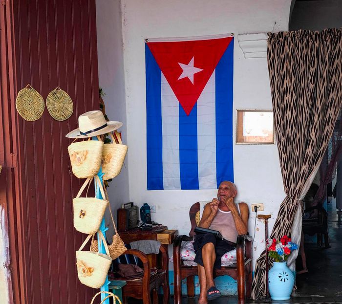 Un homme assis sur une chaise dans ce qui semble être sa maison