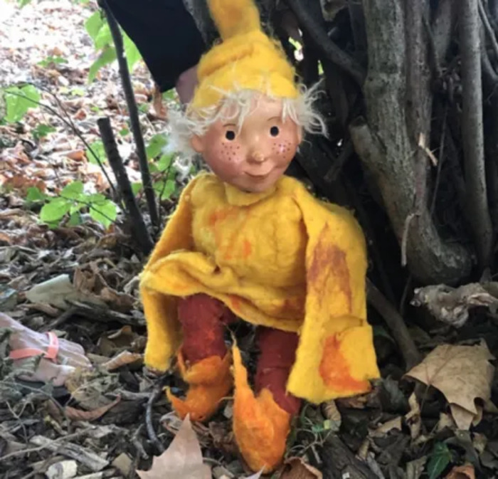 Un lutin habillé en jaune au pied d'un arbre