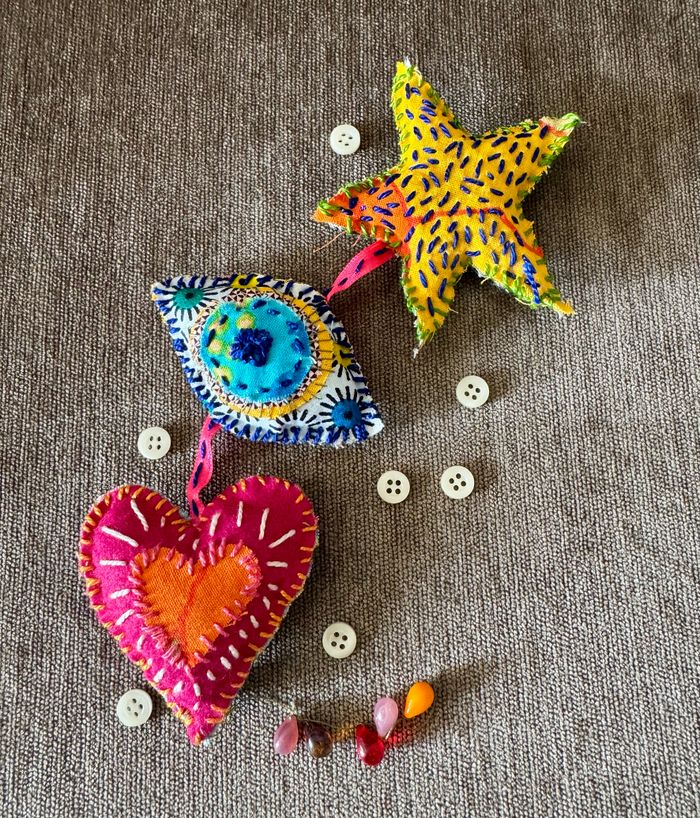 Une photo en couleur qui représente des amulettes en tissu, brodées avec des fils de couleur.