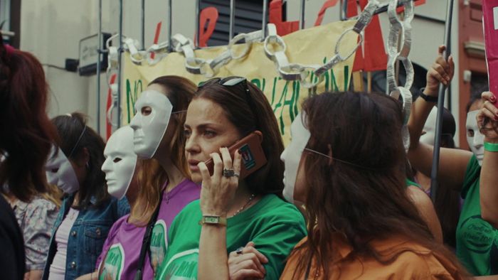 Une femme est dans une manifestation et est au téléphone.
