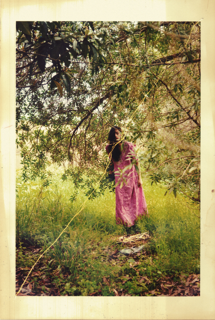 Une photo usée d'une jeune femme habillé en rose sous un arbre