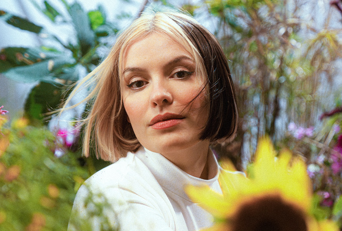 DR Hélène Sio entourée de plantes et fleurs colorées