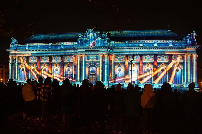 Public devant la façade illuminée du musée