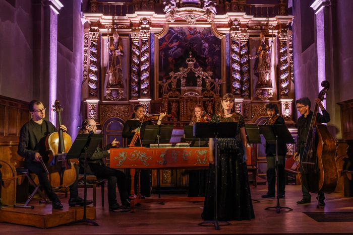 L’Ensemble Temenos en concert dans une église, avec chanteuse, instruments à cordes et clavecin.
