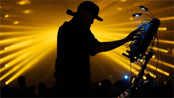 Un homme DJ en ombre sur un fond de lumière led jaune.
