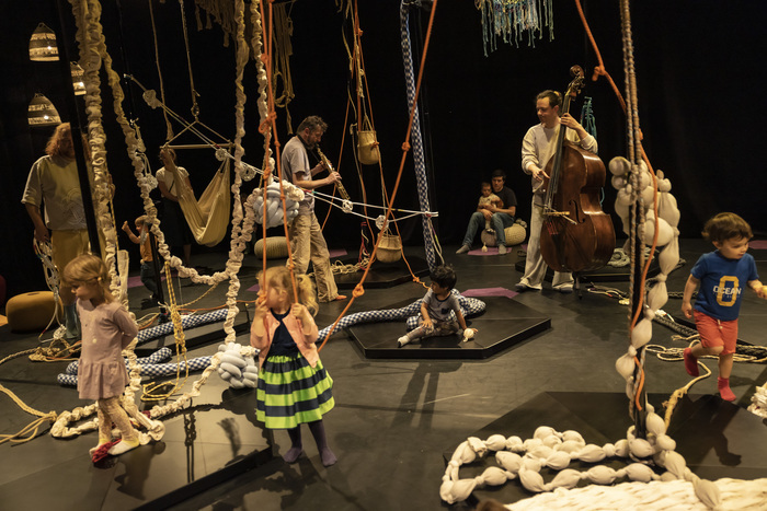 Des enfants et des artistes sur la scène parmi des cordes avec des noeuds qui pendent