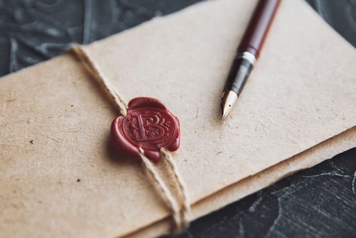 Une photo en couleur qui représente une enveloppe cachetée avec un rond de cire rouge.