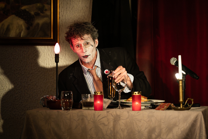 Un homme à table avec  un maquillage clownesque