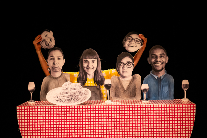 La première fois... (c) Carole Parodi On voit quatre amis assis autour d'une table dressée et garnie de verres de vin et de spaghettis. Tous les objets et personnages sont des aplats de photos manipulés par une comédienne.