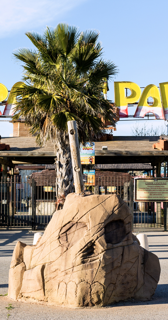 Des faux palmiers en plastique à l'entrée d'un parc d'attraction ou d'un parc aquatique.
