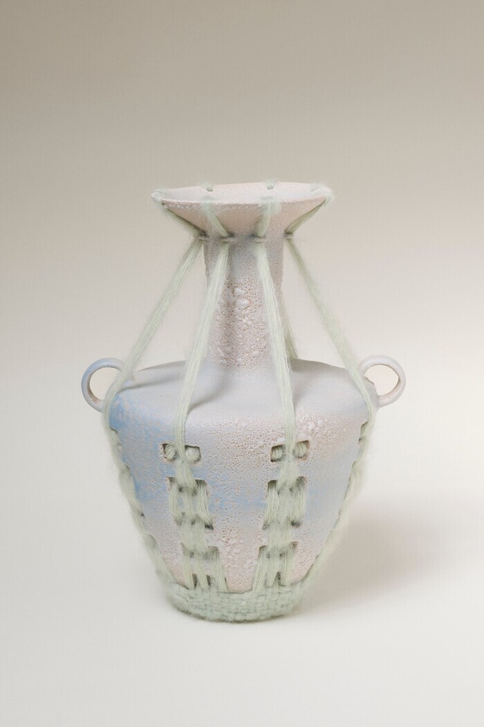 Photo d'un vase avec des perforations qui font support à un tissage en laine