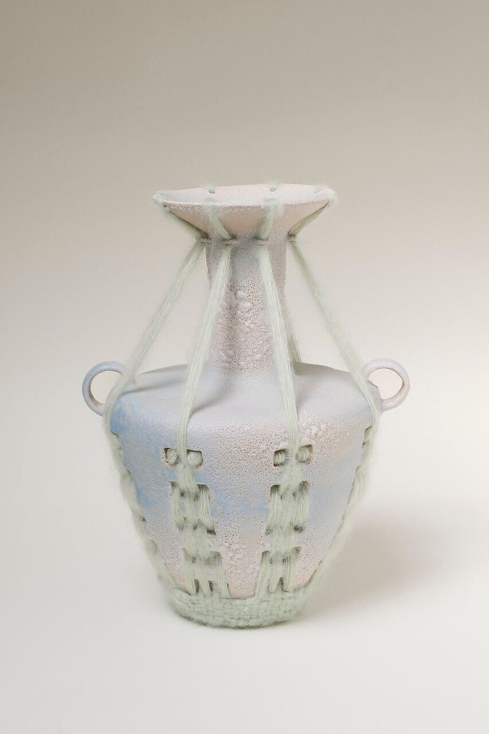Photo d'un vase avec des perforations qui font support à un tissage en laine