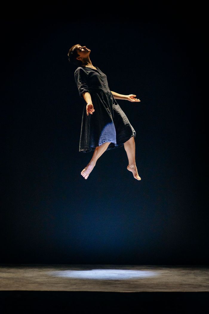 Sur scène, une femme flotte dans les airs, les yeux fermés et les bras ouverts.