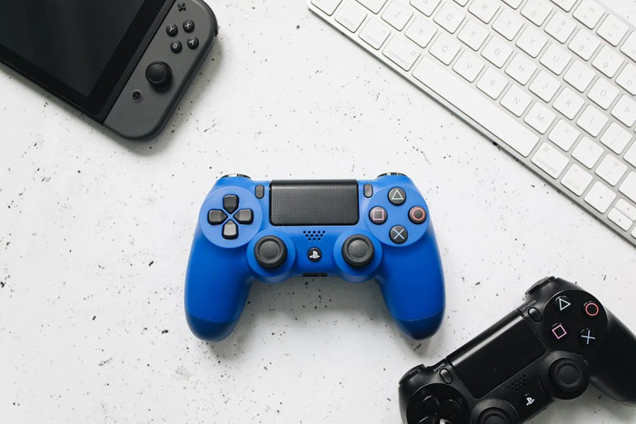 Pexels Une manette bleue posée entre des manettes noires, Switch et un clavier