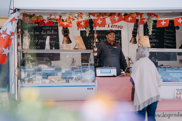 Nous voyons un marchand qui vend du fromage du valais dans son food truck à une cliente