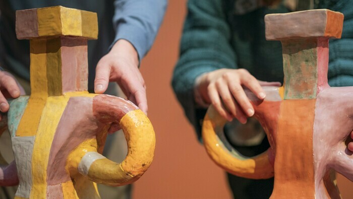 Deux personnes touchent la surface d’œuvres en céramique dans l'exposition "Marie Ducaté. Simultanés"
