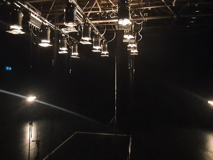 Cette image montre une dizaine de projecteurs de théâtre dirigés vers une scène vide.