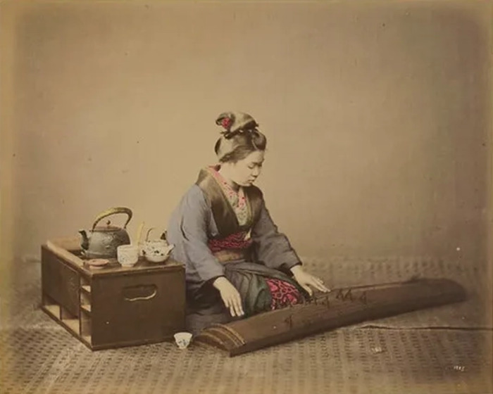 Deux personnes vêtues de blanc se tenant l’une contre l’autre, échangeant un baiser séparé par un voile blanc transparent.