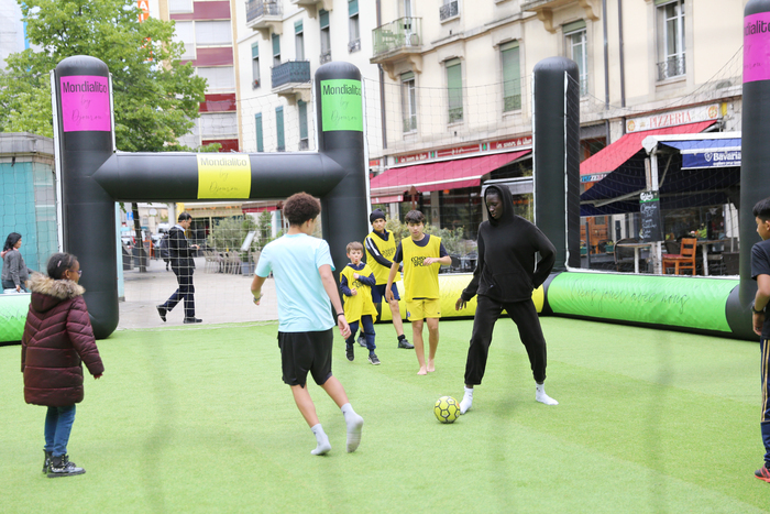 Enfants jouant au foot sur un terrain.