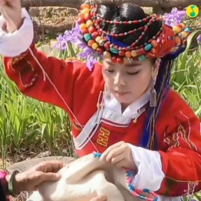 Jeune fille Moso qui coud un vêtement à la main.