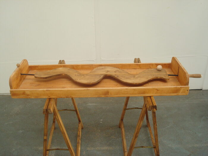 Jeu en bois avec un planche en bois et une poignée qui permet de guider une bille en bois sur un parcours sinueux.