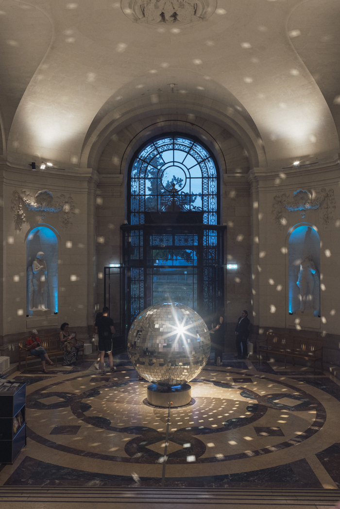 Public dans le hall du musée autour d'une boule à facettes