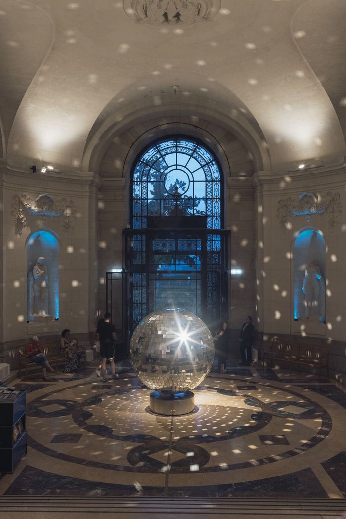 Public dans le hall du musée autour d'une boule à facettes