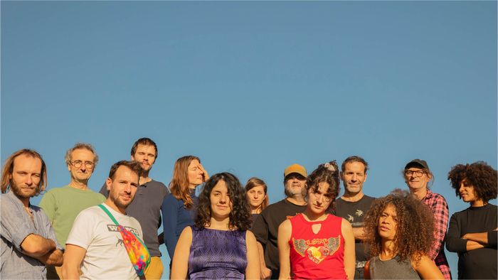 Un groupe de 13 personnes sur un ciel bleu.