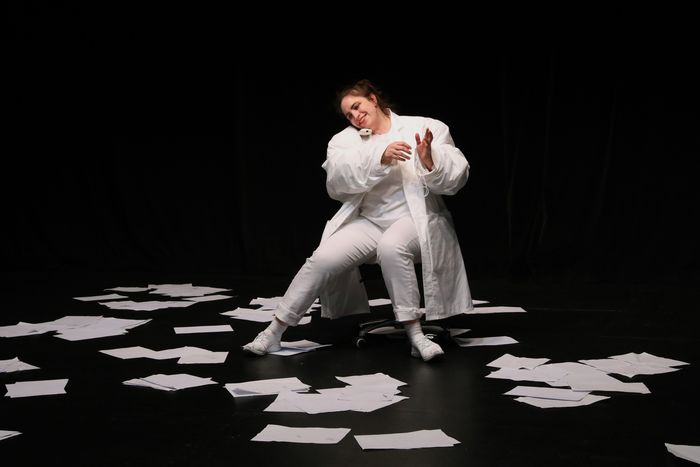 la comédienne en blanc au milieu de papiers qui virevoltent